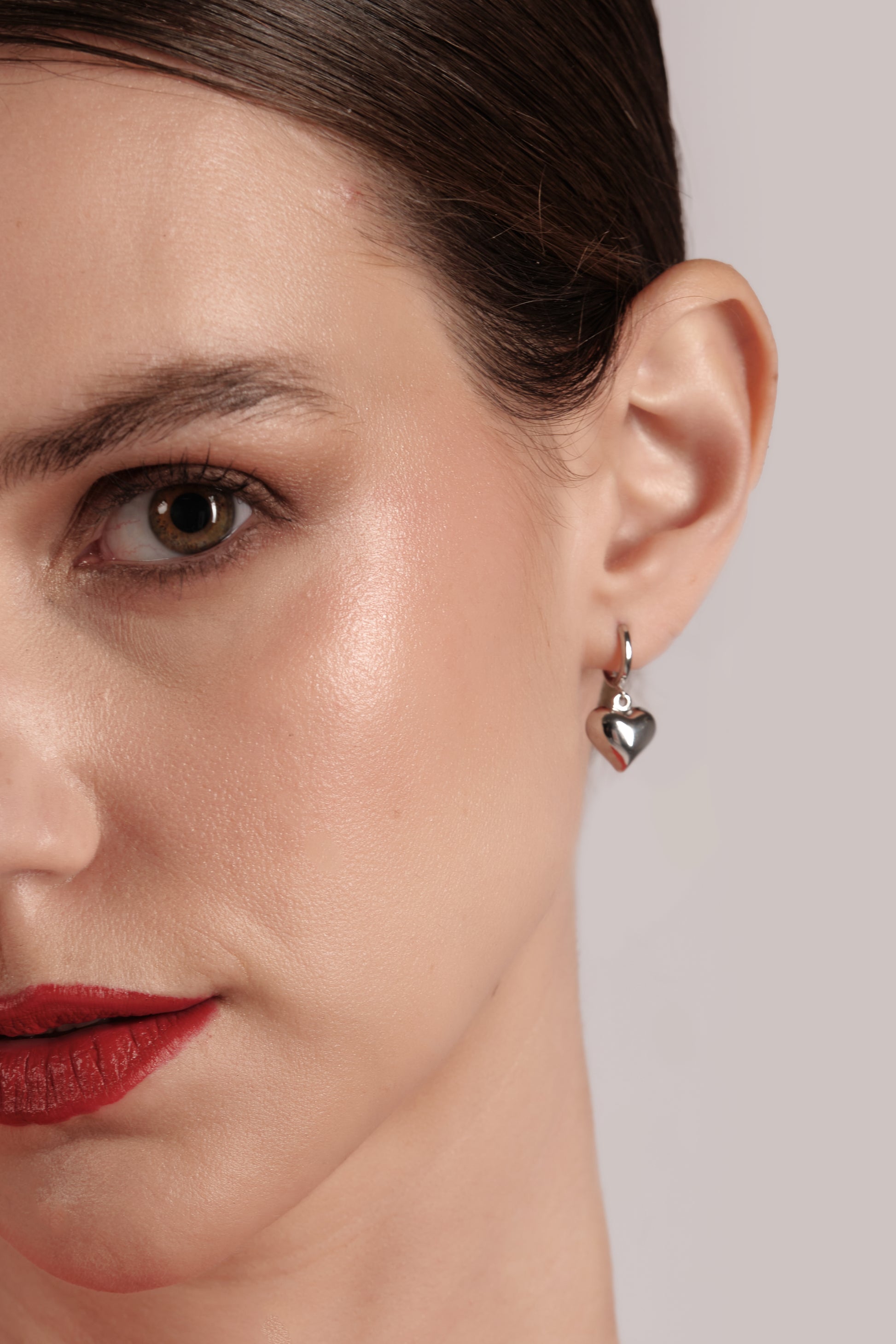 Close-up of Petite Amore Hoops — 925 sterling silver heart-shaped hoop drop earring on model