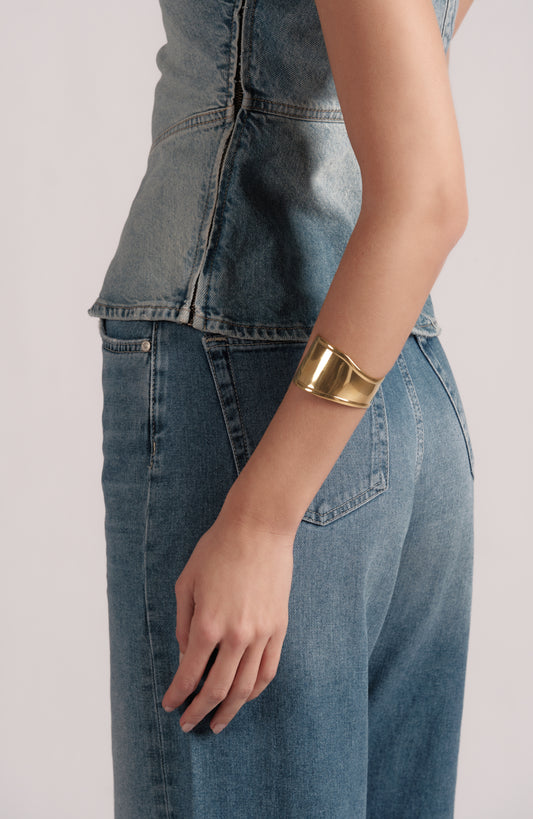Close-up of Plain & Bold gold‑plated stainless steel sculptural cuff bracelet on model wrist